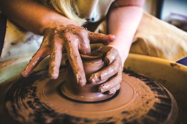 Hands working clay on a pottery wheel