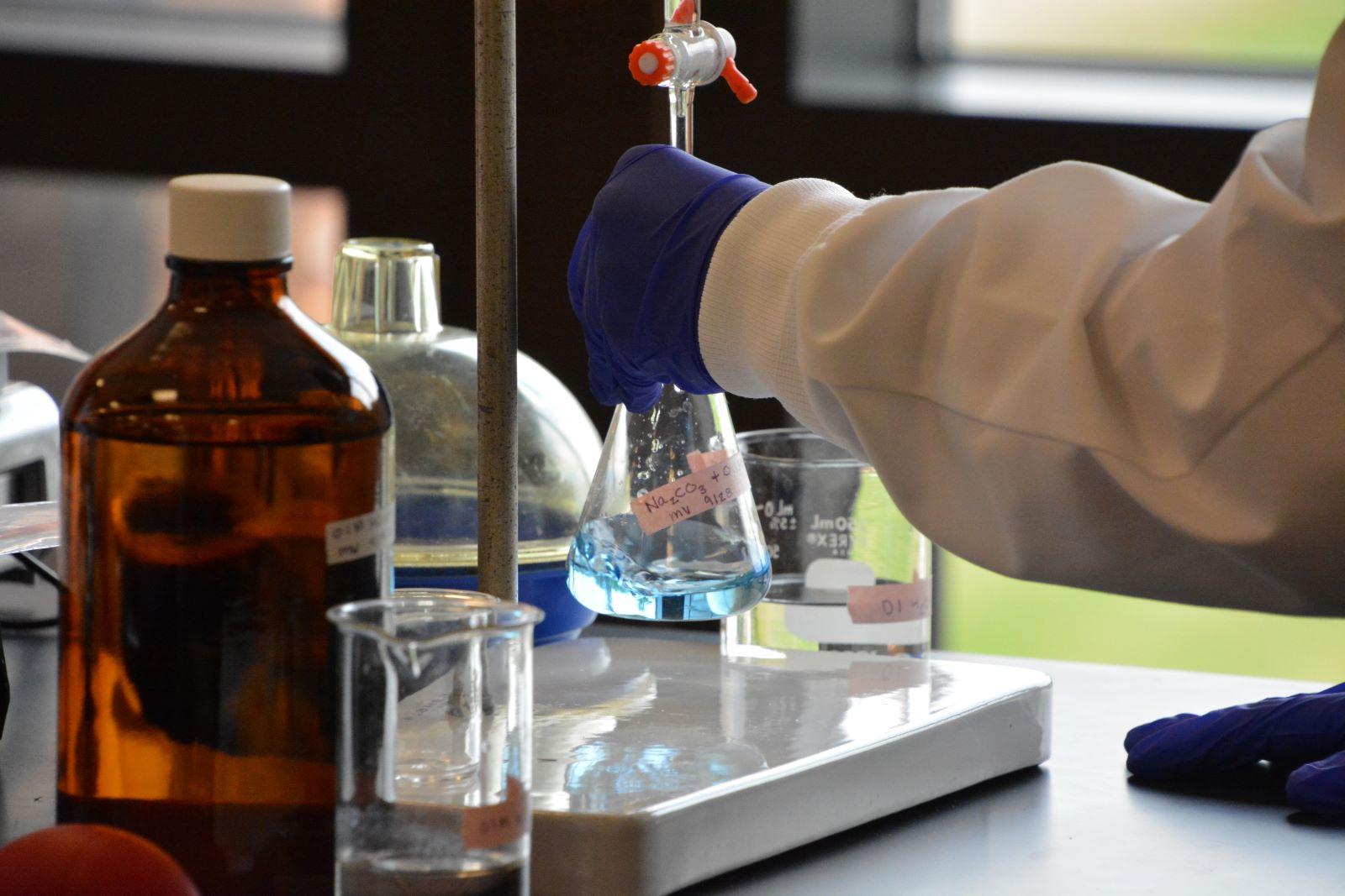 Student's hands working with beakers and solutions in the chemistry lab