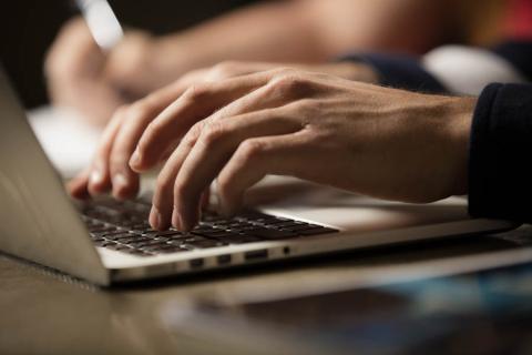 student typing on laptop