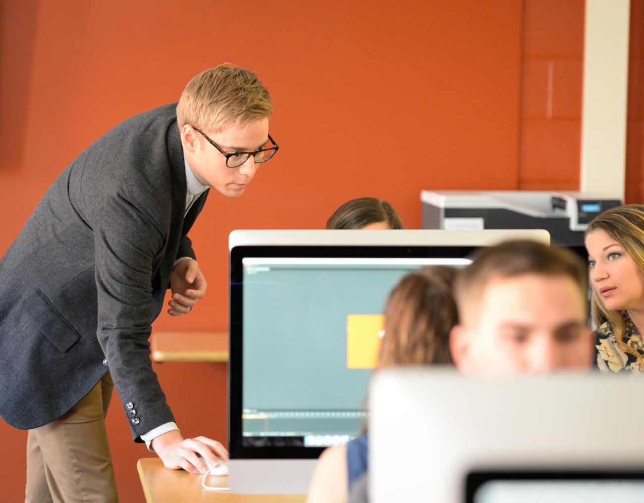 Professor works with students in computer lab.