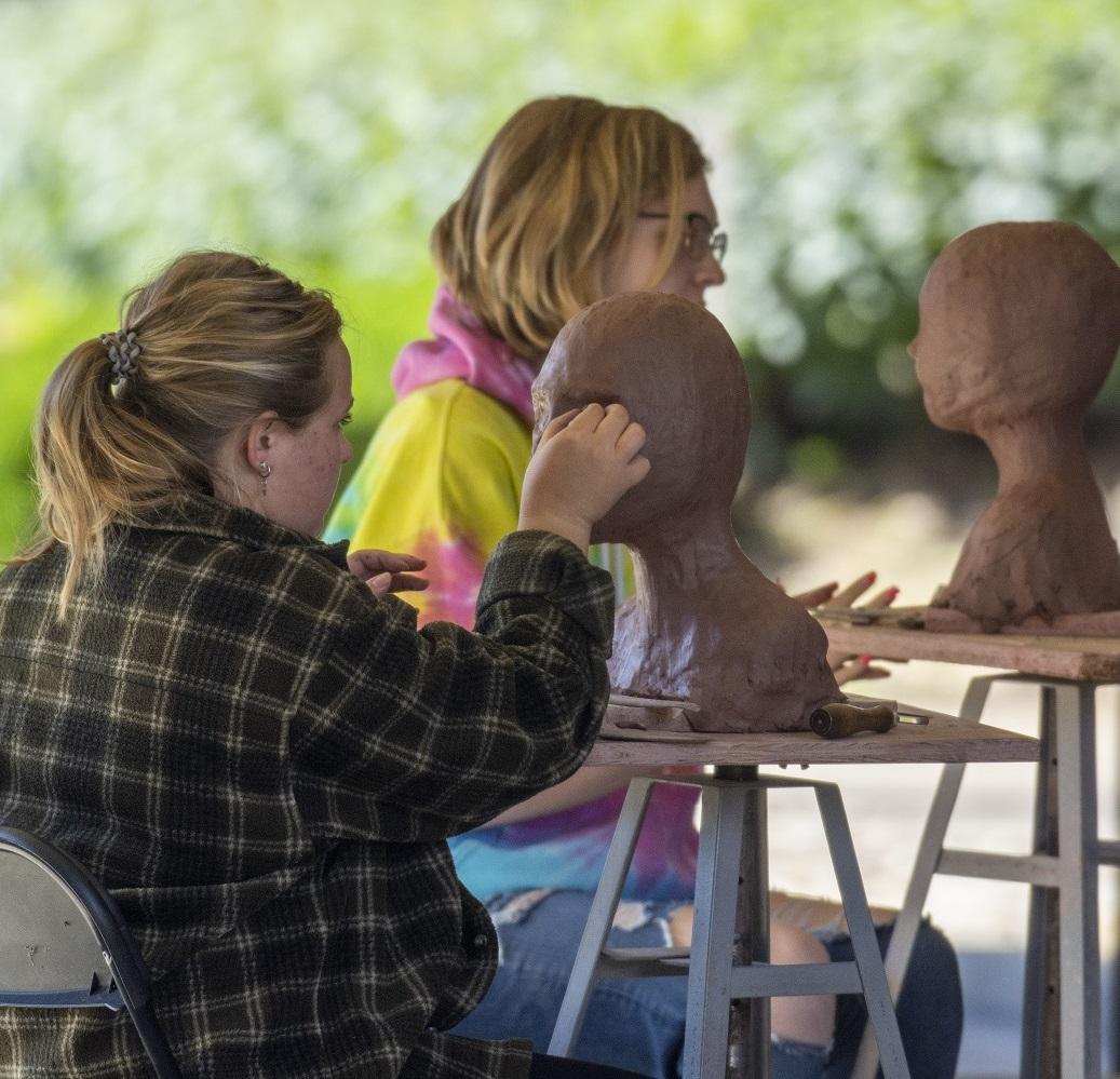 student in outdoor art class creating a sculpture 