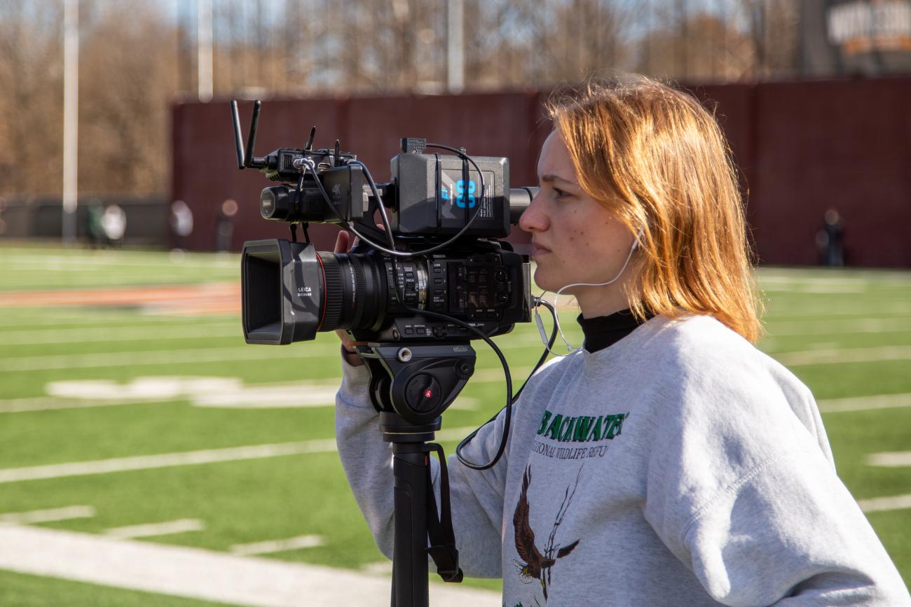 Waynesburg Communication student filming on the football field