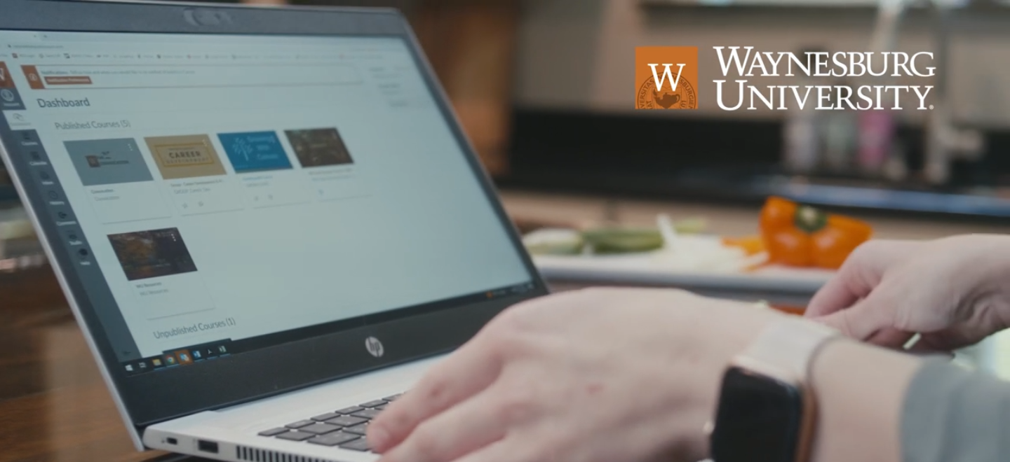 Student typing on laptop in kitchen while preparing dinner