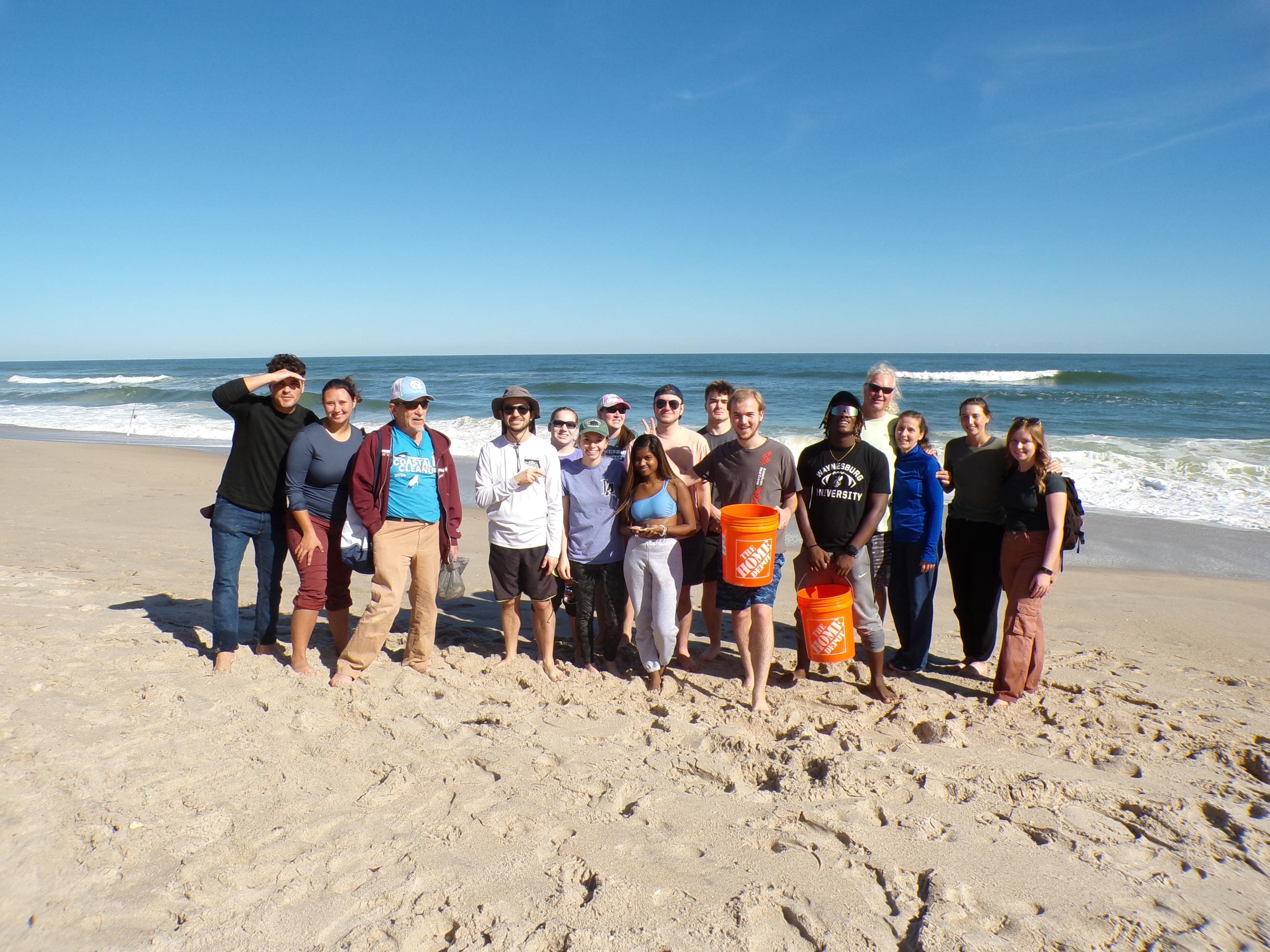 Trip participants gather together in front of the Florida waves for a beach photo 