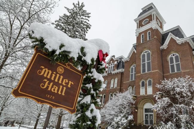 Snow and Christmas decor on the Miller Hall sign with Miller Hall in the background