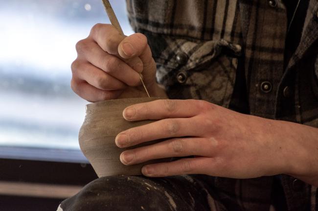 Student creates pottery in art class on campus